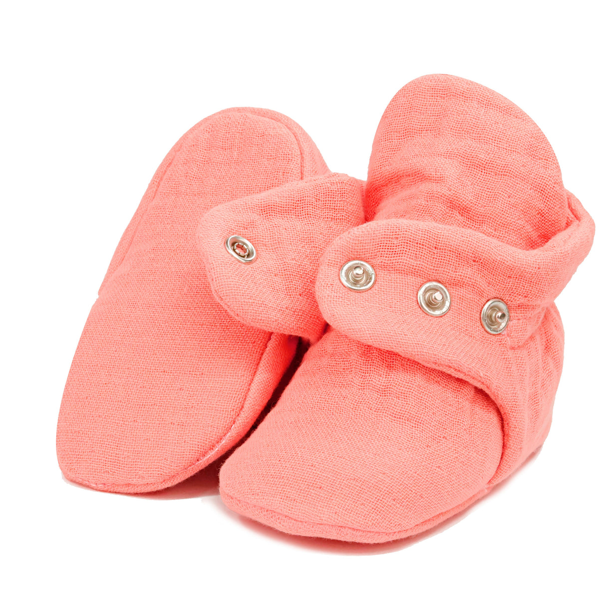 Dusty coral pink textured muslin baby booties with snap straps, showing one sole and an open snap strap on white.