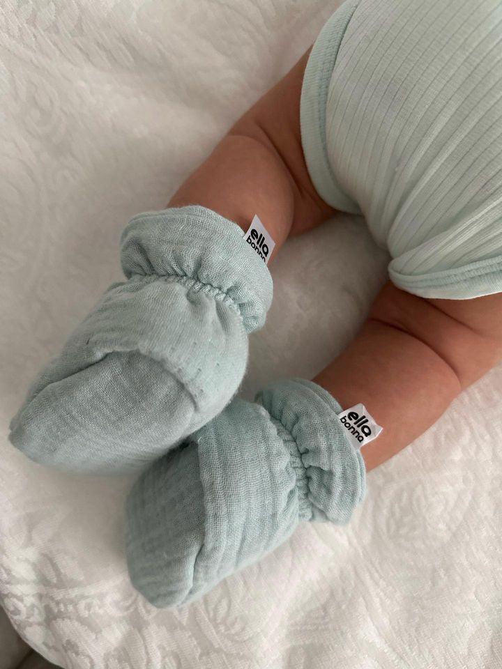 Close-up of mint booties with soles partly visible on a baby.