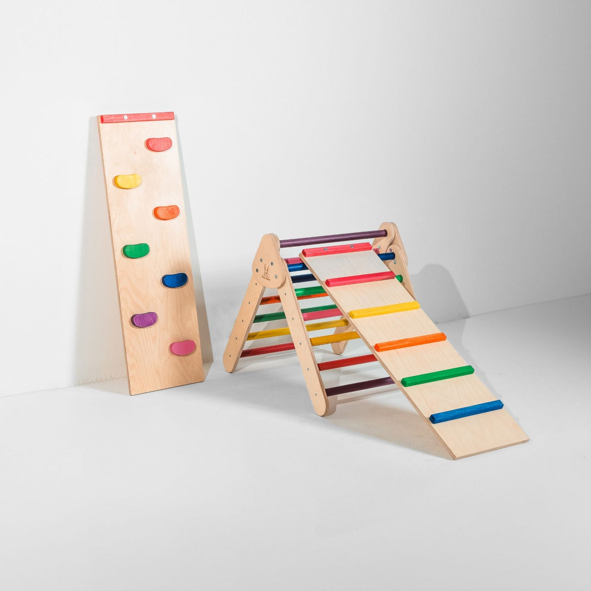 Small rainbow-rung triangle with attached ladder ramp and a climbing-hold ramp beside it.