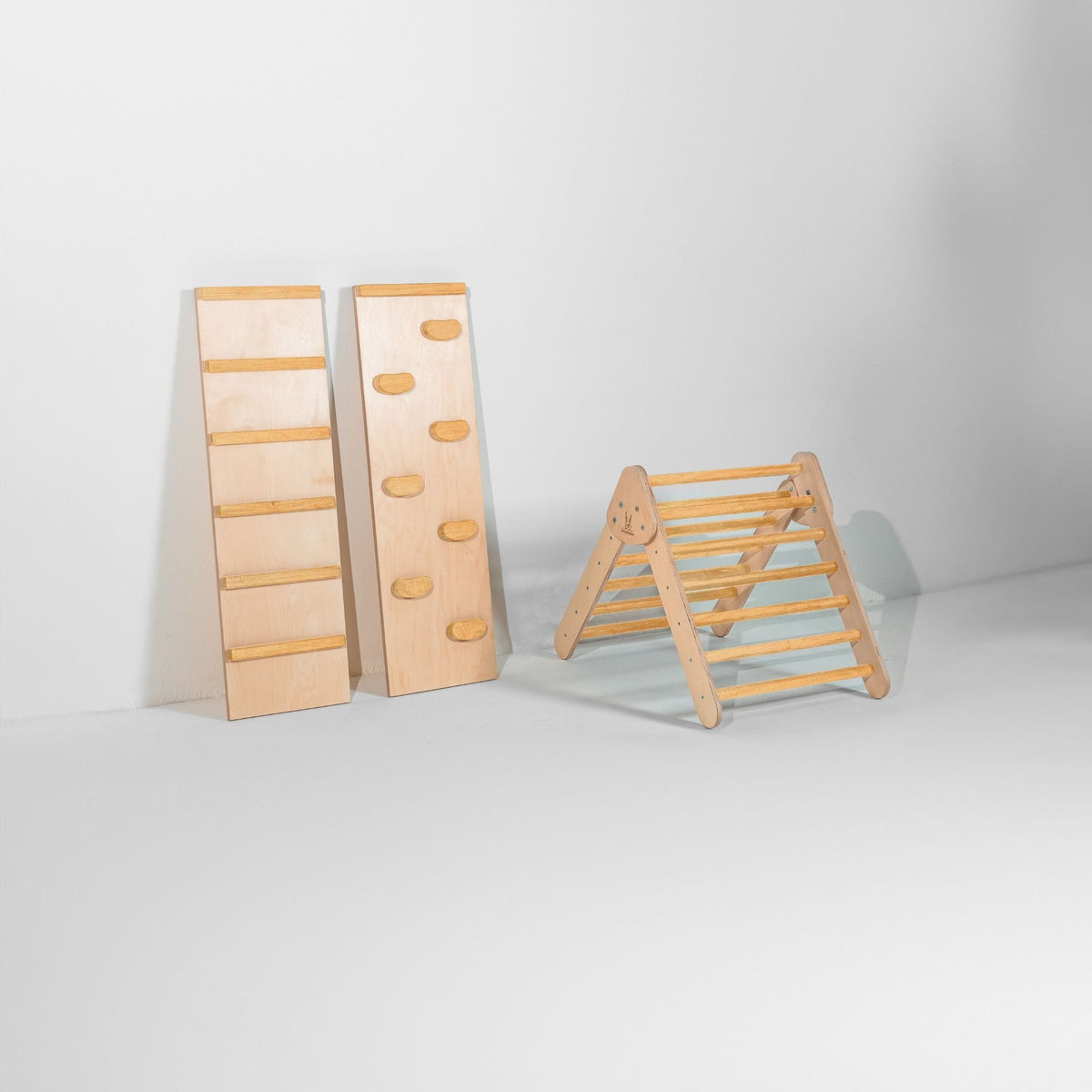 Small golden-tan-rung climbing triangle beside upright ladder and climbing-hold ramps.