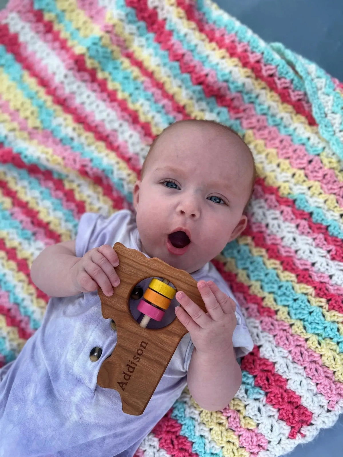 Lifestyle photo showing a wooden state rattle with a child