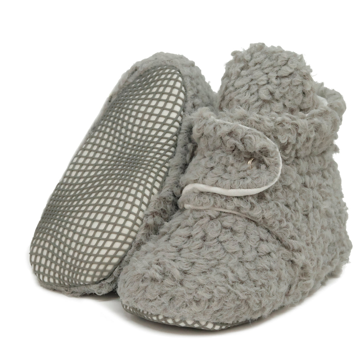 Gray teddy-texture baby booties with snap straps and gray grip soles, with one sole facing the camera on a white background.