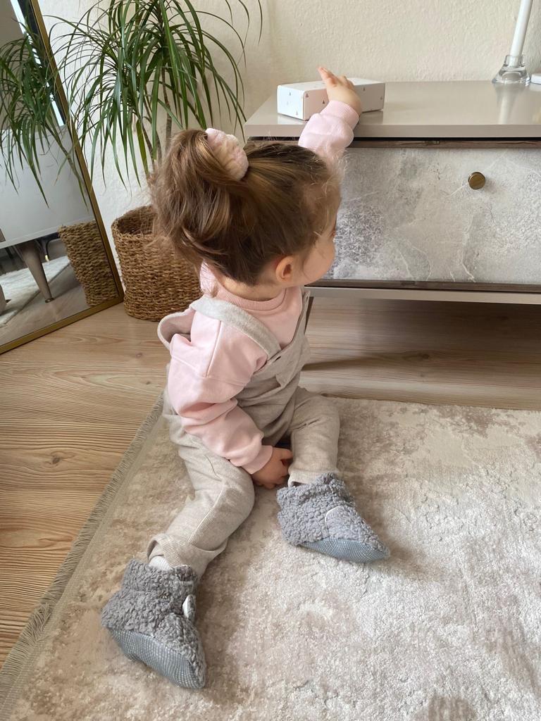 Child climbing stairs wearing gray teddy booties.