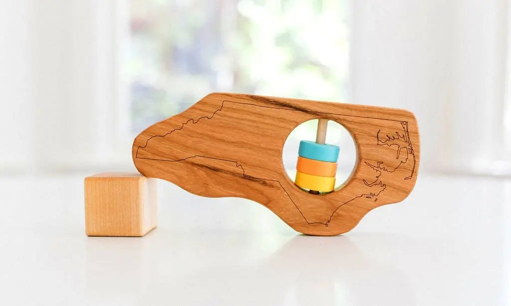 Bannor Toys North Carolina State Wooden Baby Rattle, showing state-shaped cherry-wood body and colored rattle discs