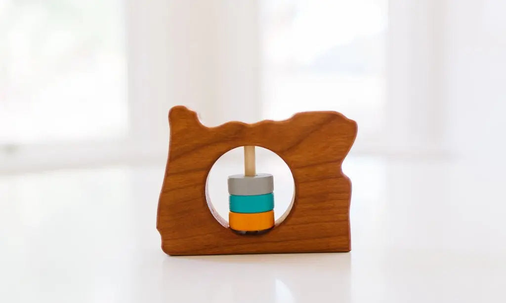 Bannor Toys Oregon State Wooden Baby Rattle, showing state-shaped cherry-wood body and colored rattle discs