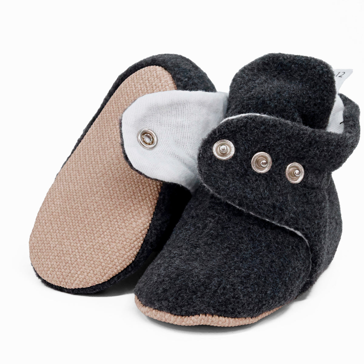 Charcoal fleece-texture baby booties with snap straps and tan soles, showing one sole and an open snap strap on white.