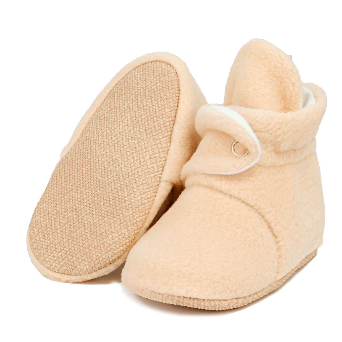 Beige fleece-texture baby booties with snap straps and tan soles, with one sole facing the camera on a white background.