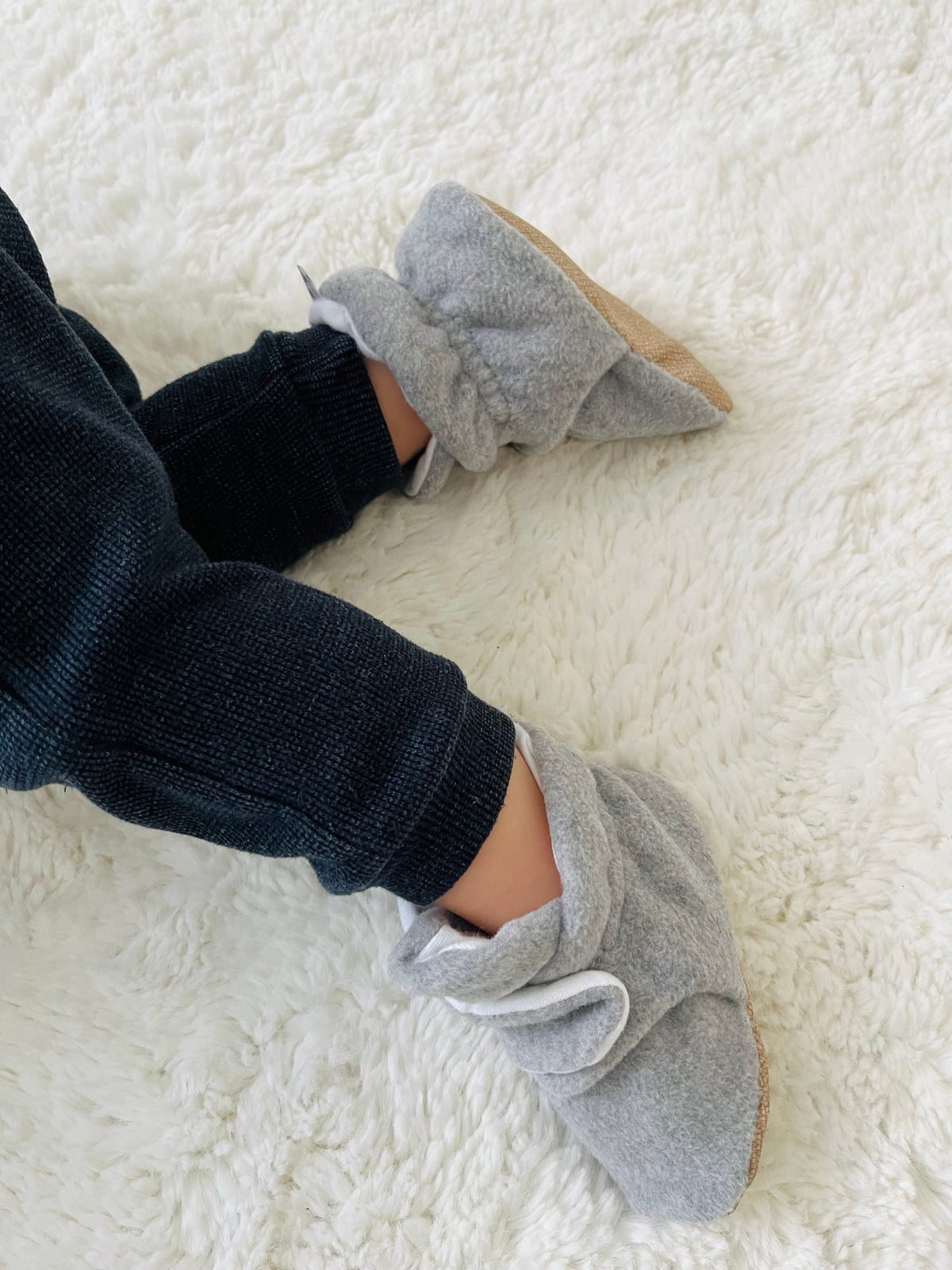 Side close-up of gray booties worn with dark trousers.