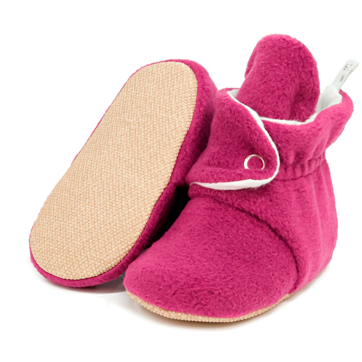 Purple fleece-texture baby booties with snap straps and tan soles, with one sole facing the camera on a white background.
