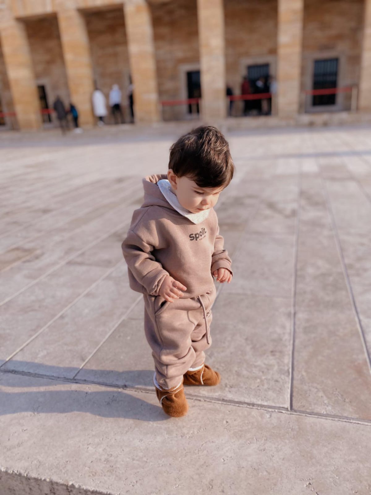 Child standing outdoors wearing brown booties.