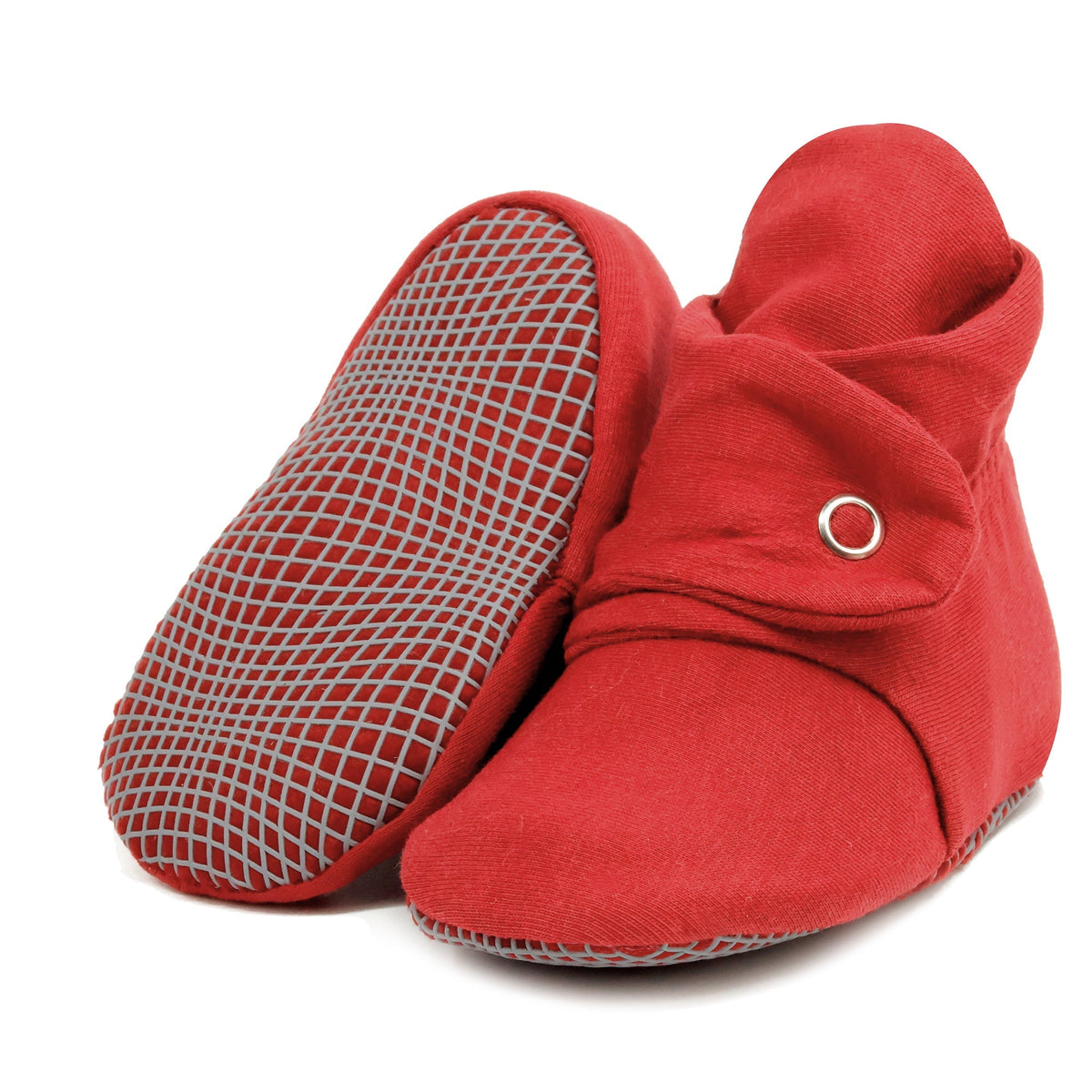 Burgundy fabric baby booties with snap straps and gray grip soles, with one sole facing the camera on a white background.
