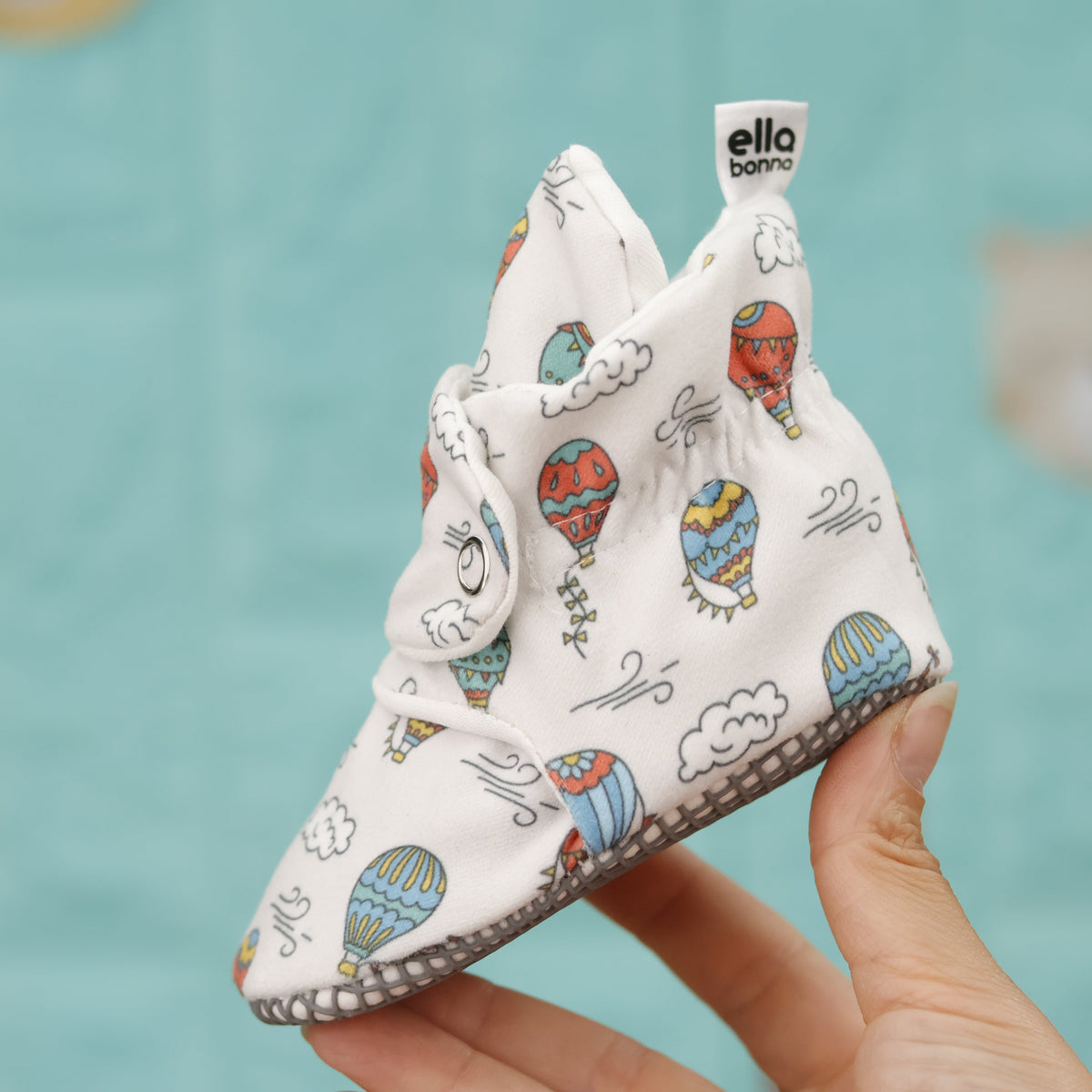 Single balloon-print bootie held in a hand, side view.