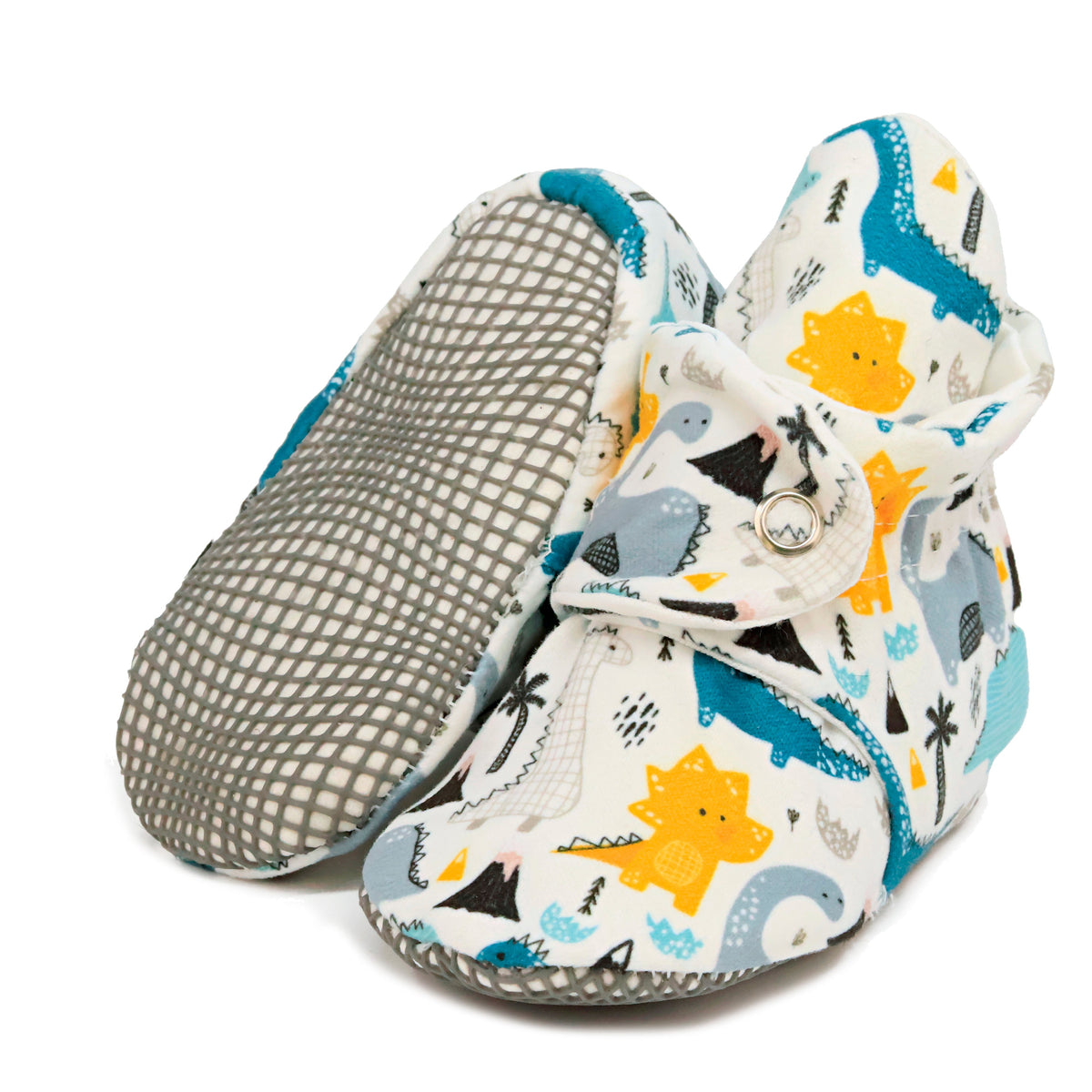 Cream baby booties with blue, gray and yellow dinosaurs and snap straps, with one sole facing the camera on a white background.