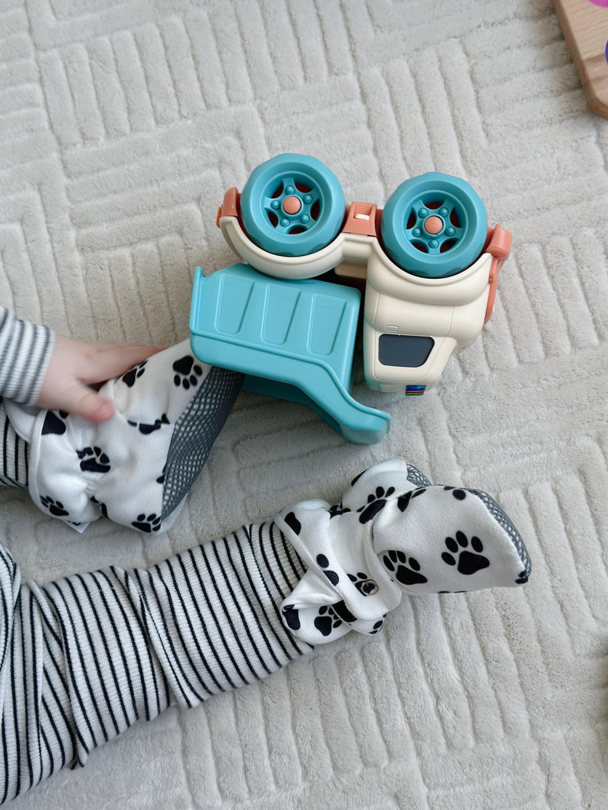 Paw-print booties worn beside an overturned toy truck.