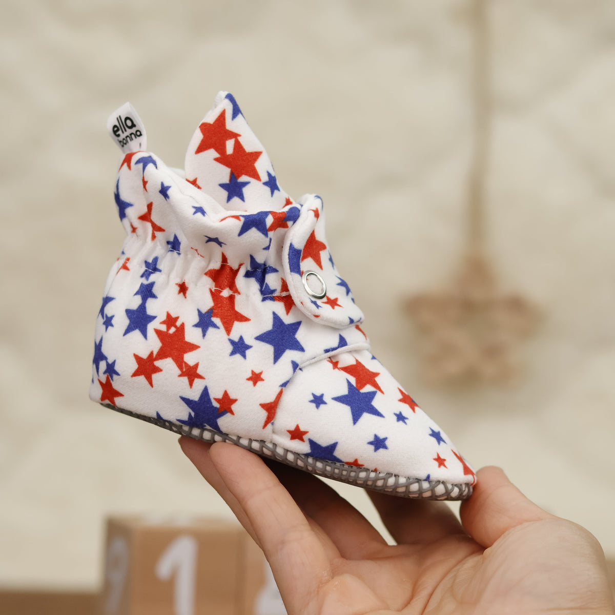 Single star-print bootie held in a hand, side view.