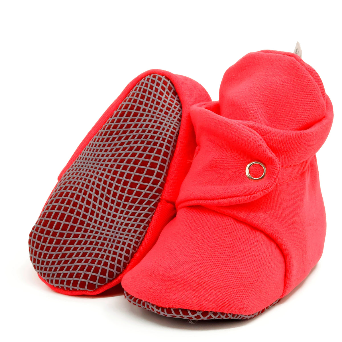 Bright red fabric baby booties with snap straps and gray grip soles, with one sole facing the camera on a white background.