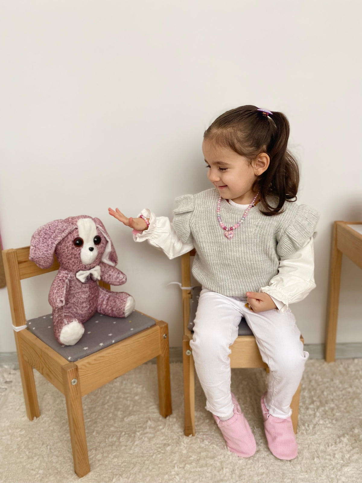 Child seated at a small table wearing pink corduroy moccasins.