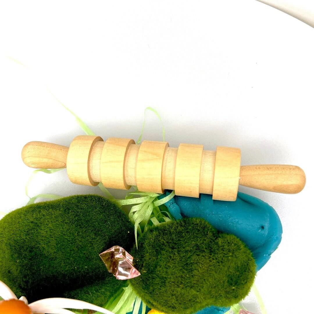 Grooved rolling pin above green decorations and blue playdough in the Pixie Hollow kit