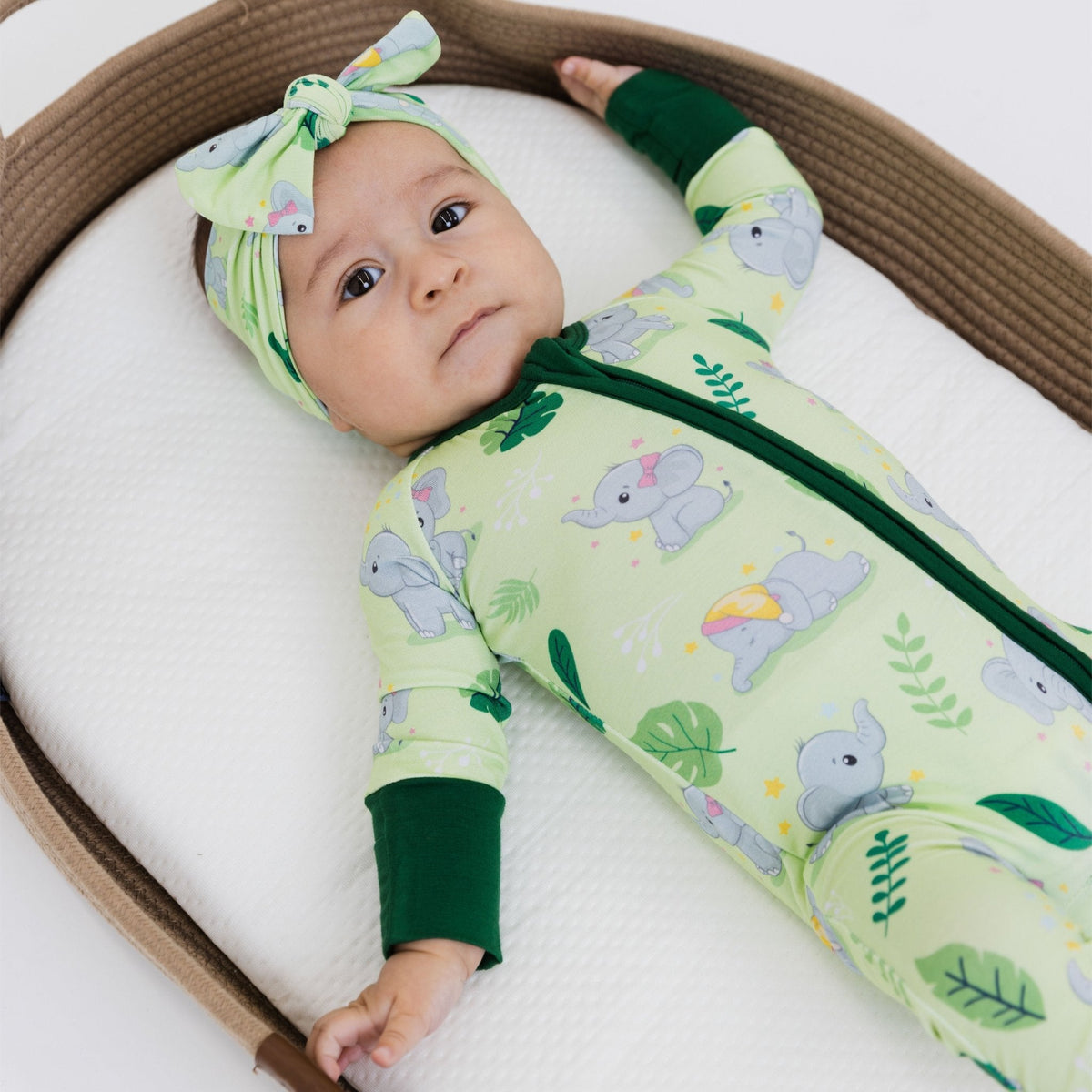 Baby lying with one hand raised while wearing Bam & Stitch Playfully Strong Convertible Romper.