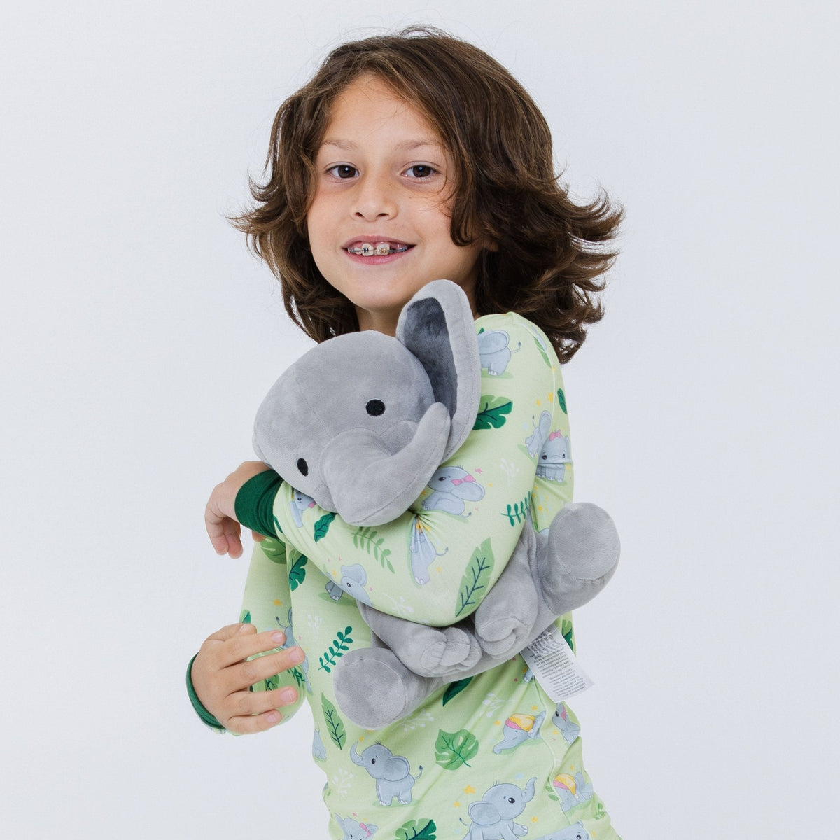 Child holding a plush elephant against their chest while wearing Bam & Stitch Playfully Strong Long Sleeve Pajamas.