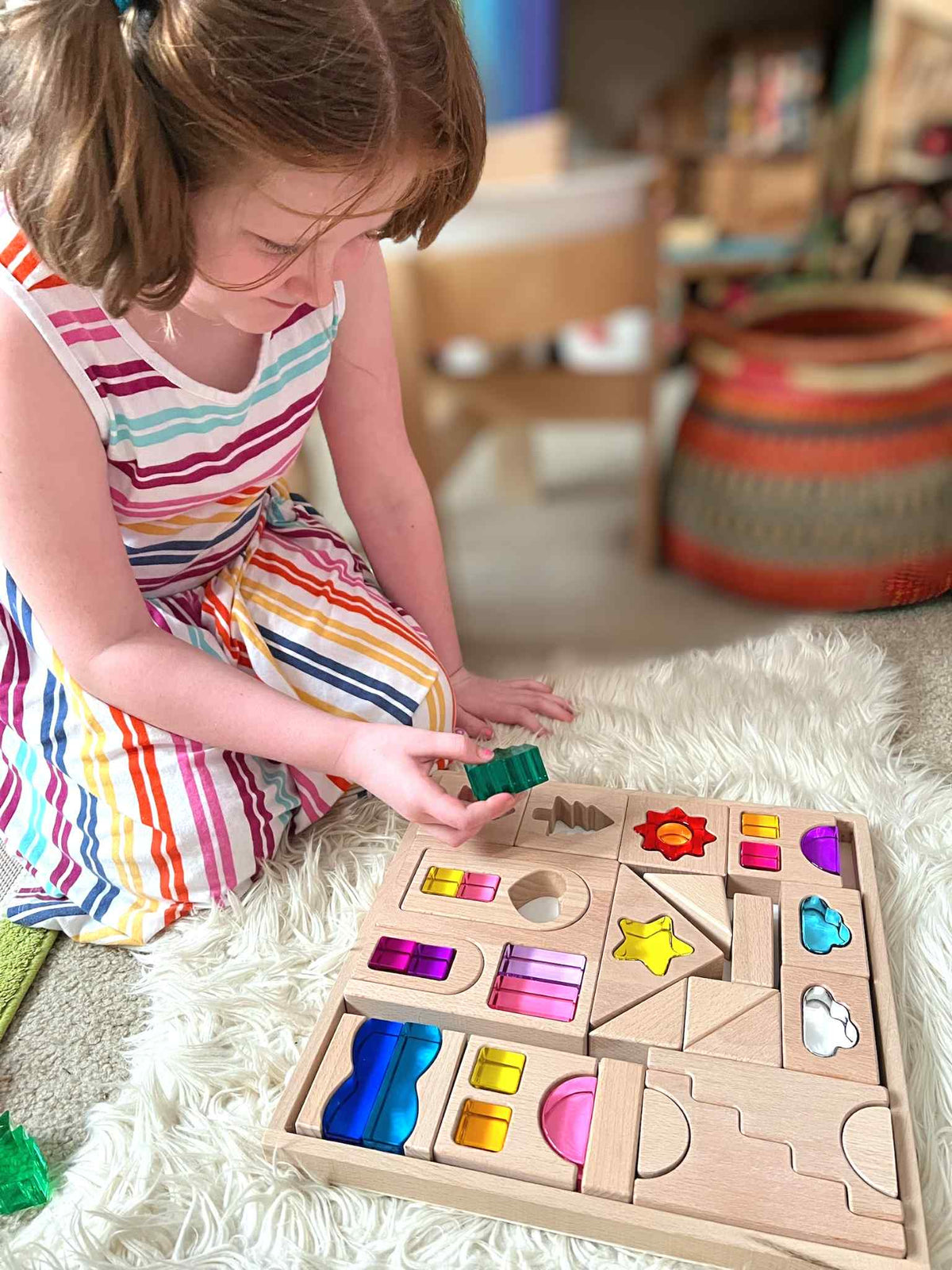 Child arranging colorful acrylic shapes in the Dreamlight Village wooden tray