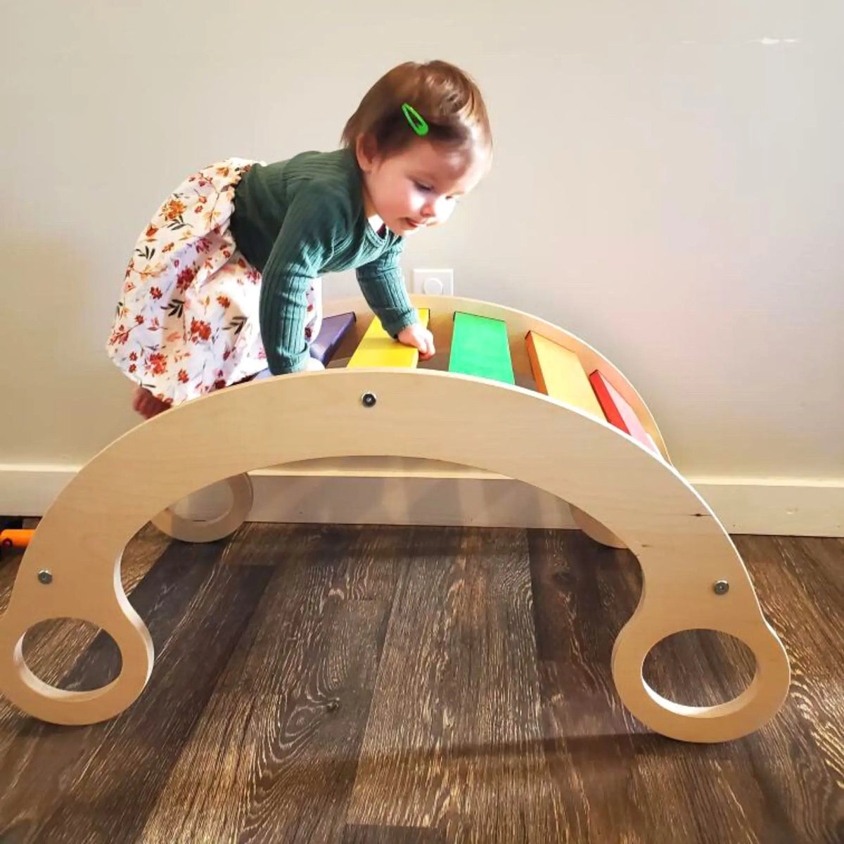Child climbing over a rainbow-slat rocker turned upside down as an arch.