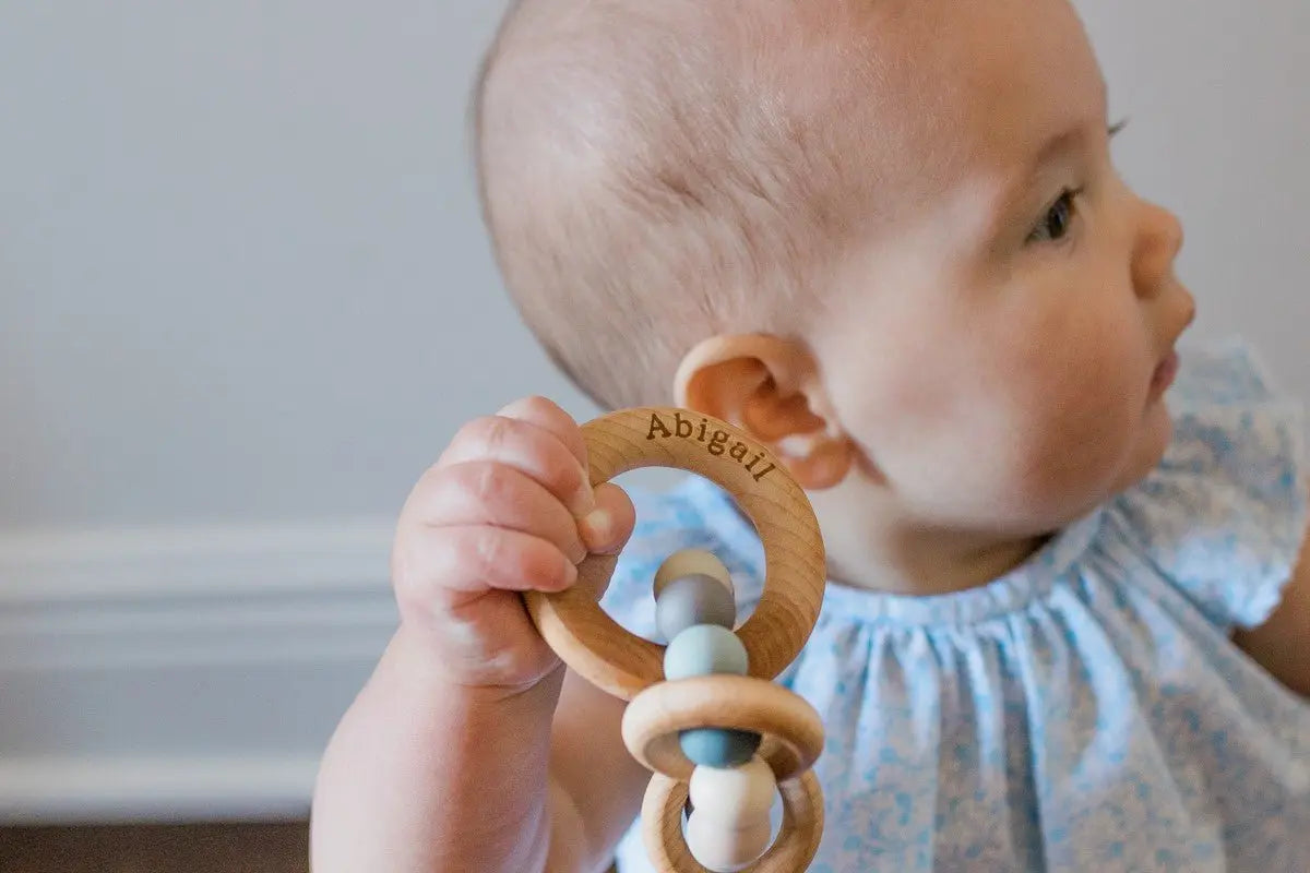 Lifestyle photo showing a wood and silicone teether with a child