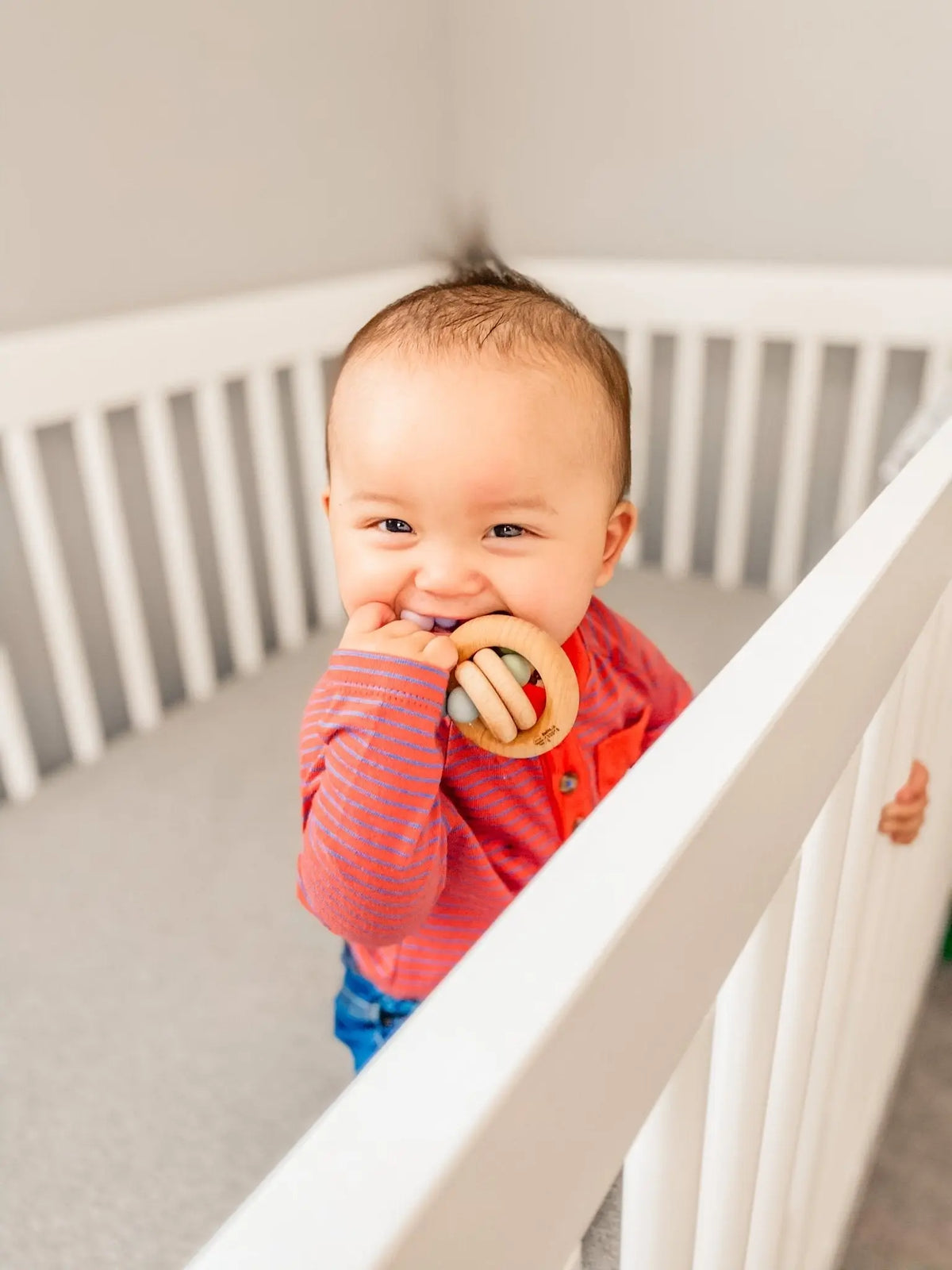 Lifestyle photo showing a wood and silicone teether with a child