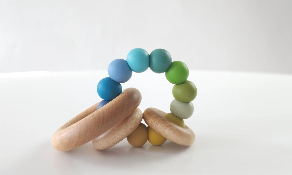 Saturn Ring Teether with blue, green and yellow silicone beads and wooden rings