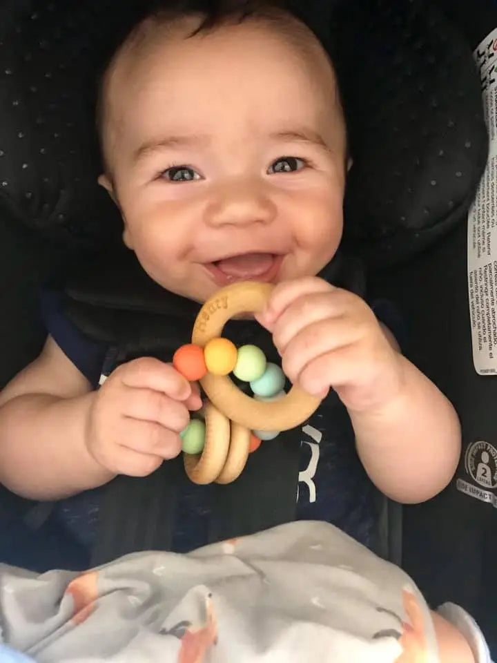 Lifestyle photo showing a wood and silicone teether with a child