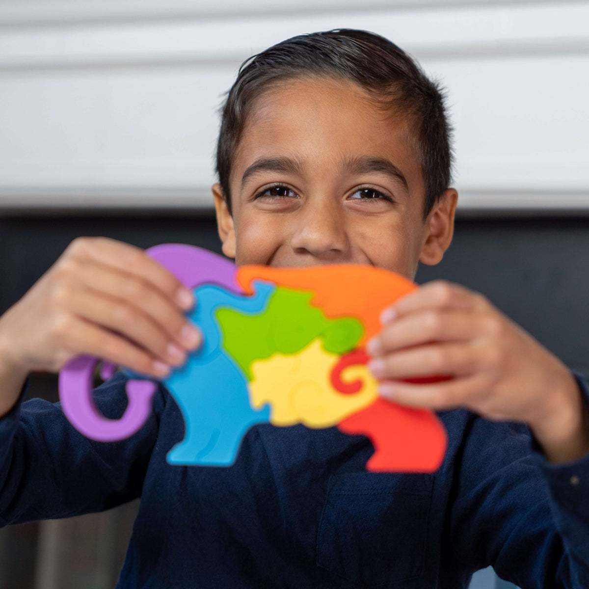 Child holding the assembled multicolored elephant puzzle