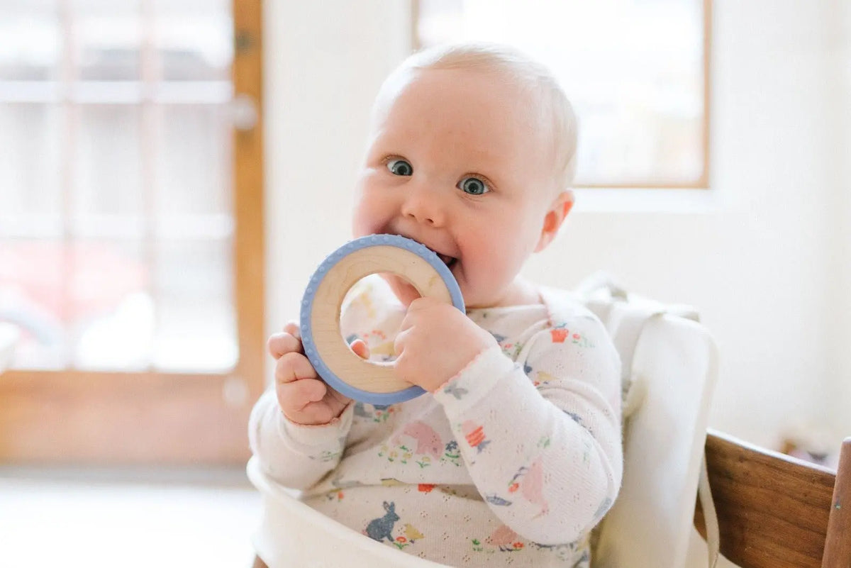 Lifestyle photo showing a wood and silicone teether with a child