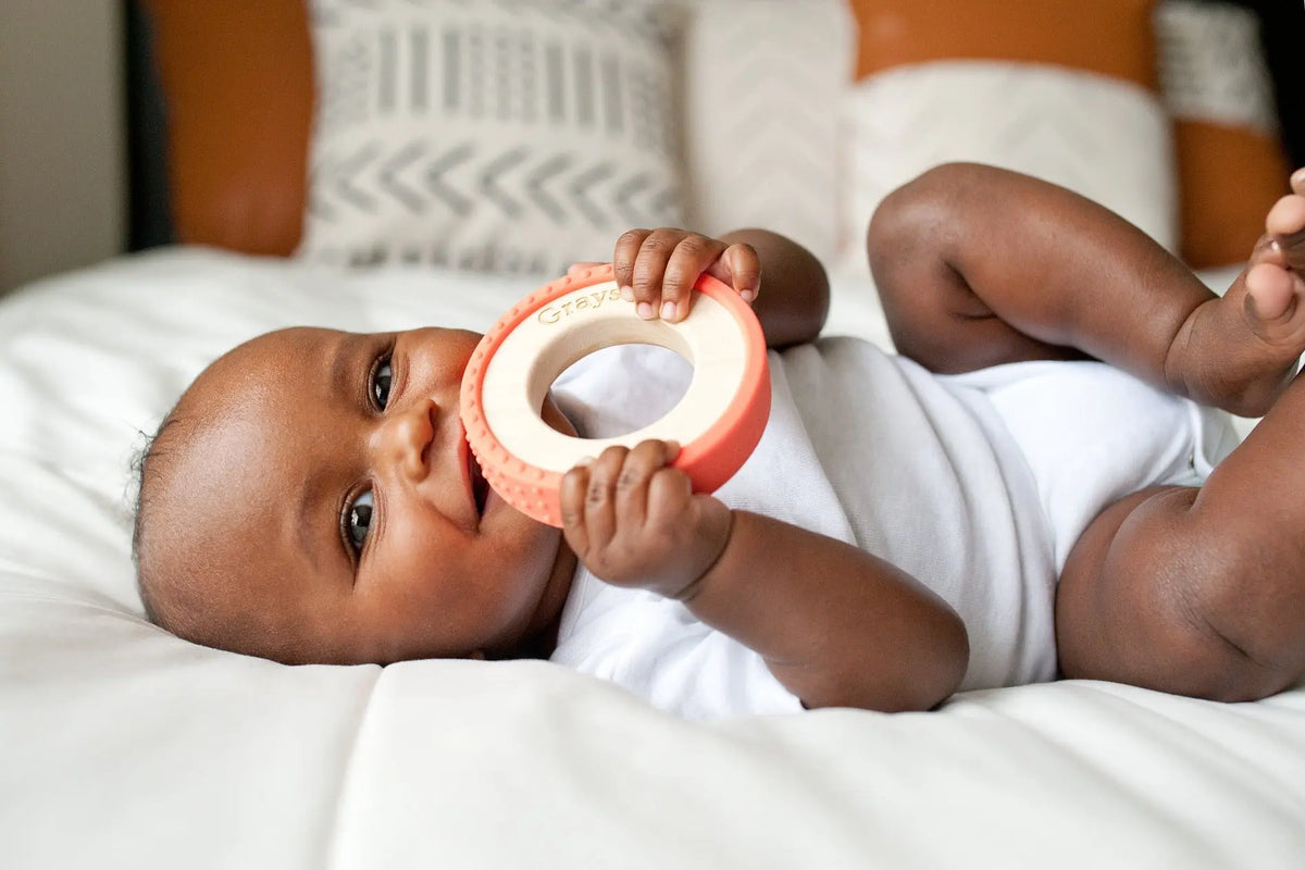 Lifestyle photo showing a wood and silicone teether with a child
