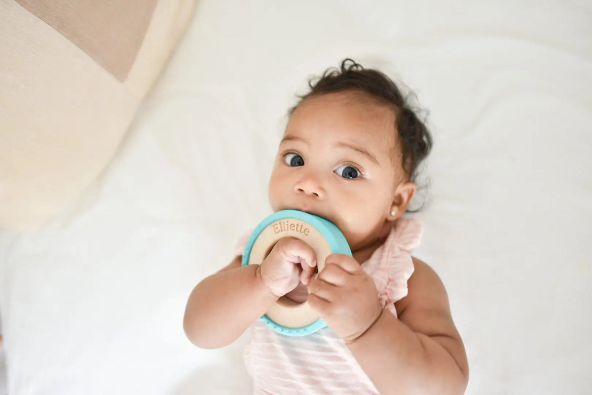 Lifestyle photo showing a wood and silicone teether with a child