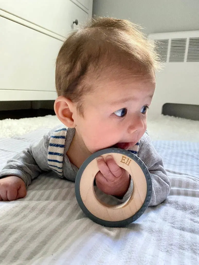 Lifestyle photo showing a wood and silicone teether with a child