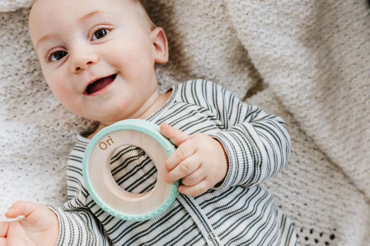 Lifestyle photo showing a wood and silicone teether with a child