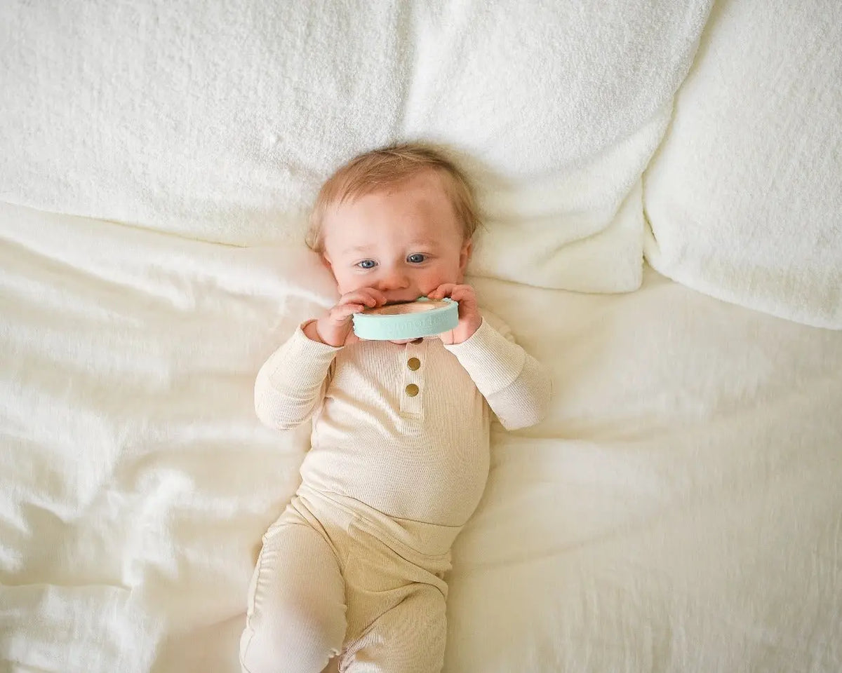 Lifestyle photo showing a wood and silicone teether with a child