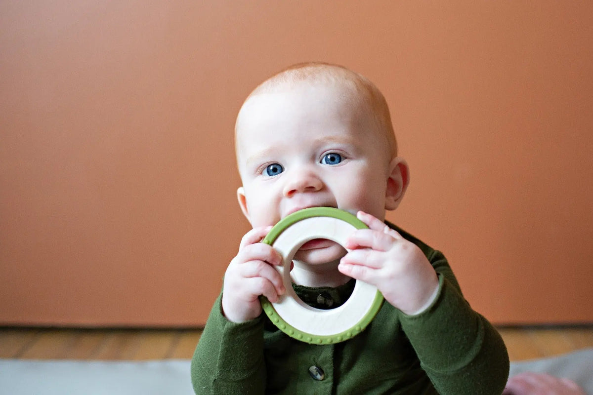 Lifestyle photo showing a wood and silicone teether with a child