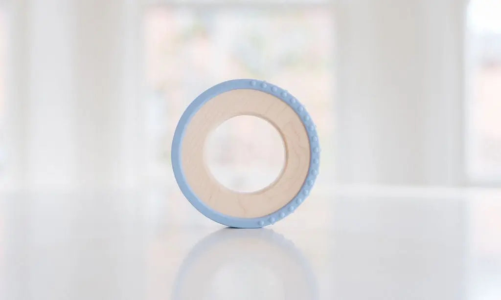 Wooden teething ring with a pale blue silicone wrap