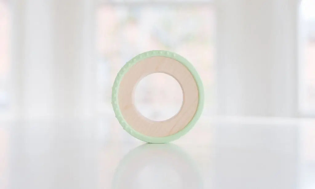 Wooden teething ring with a pale green silicone wrap