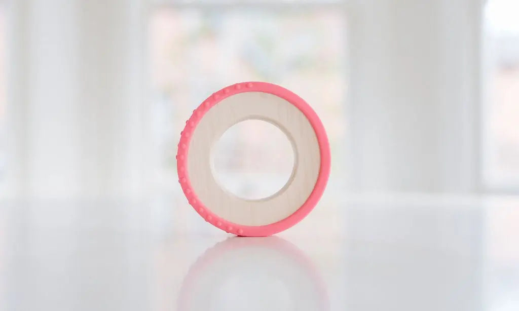 Wooden teething ring with a bright pink silicone wrap