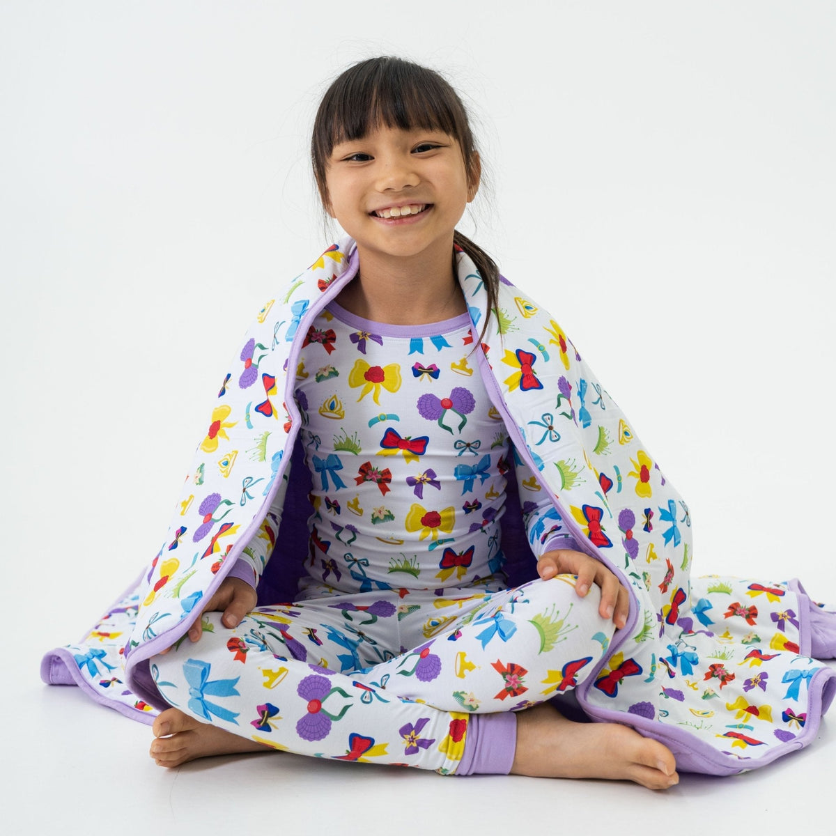 Child seated with Bam & Stitch Sparkle & Reign Blanket wrapped around them.