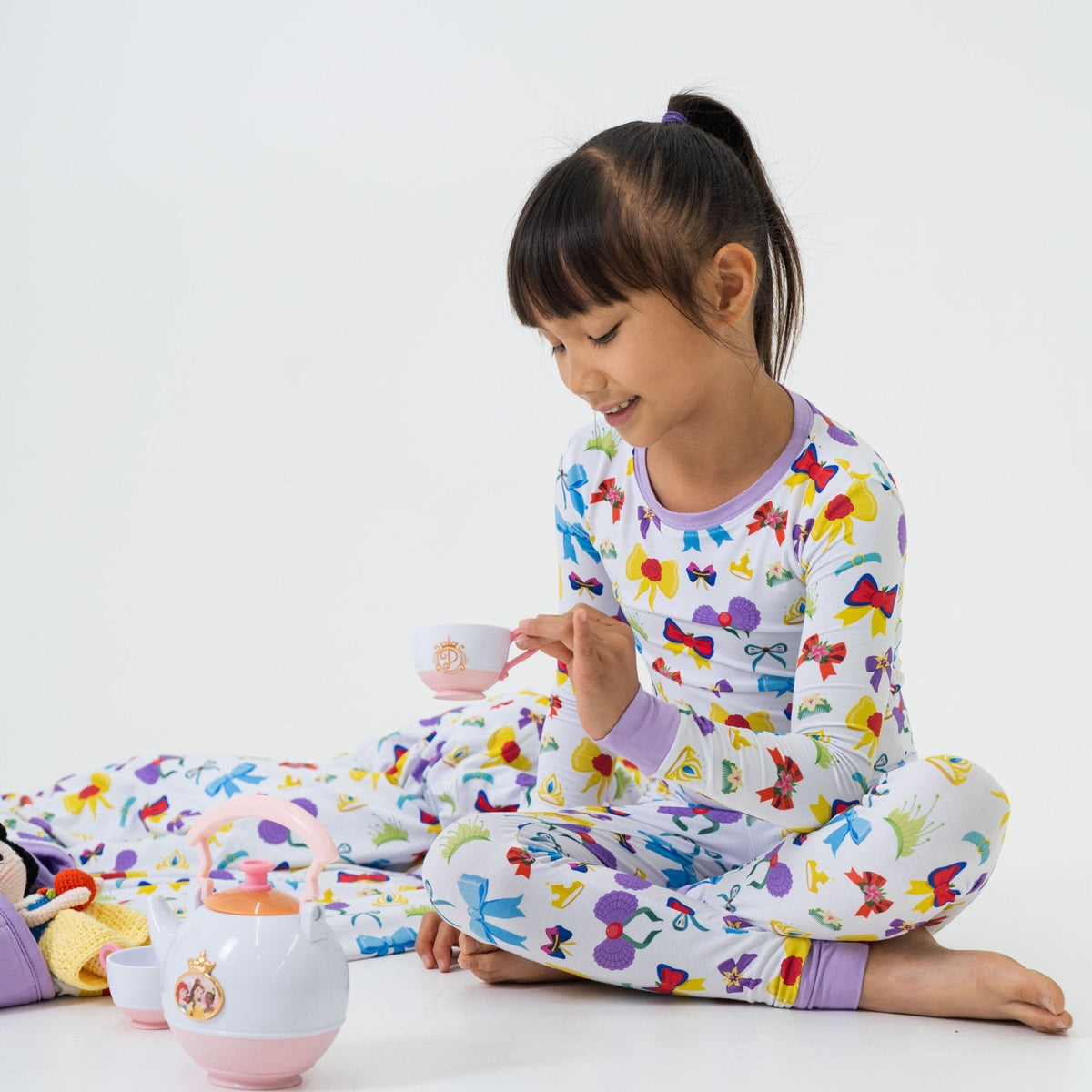 Child playing at a table while wearing Bam & Stitch Sparkle & Reign Long Sleeve Pajamas.