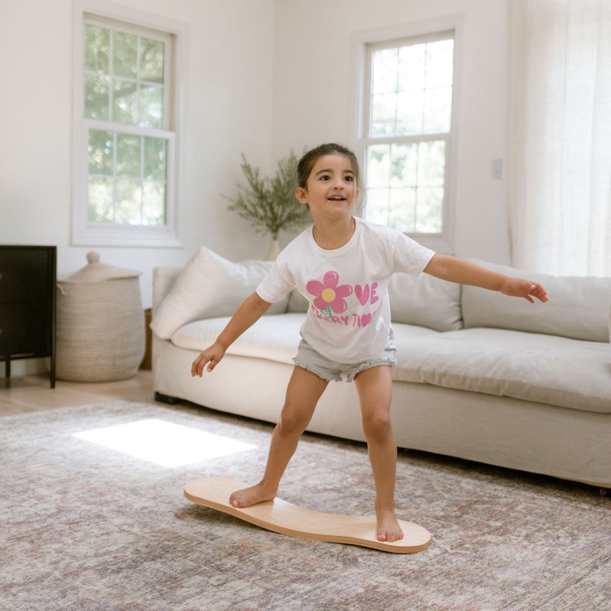 Child facing forward on a pale Spinzee board with arms outstretched.