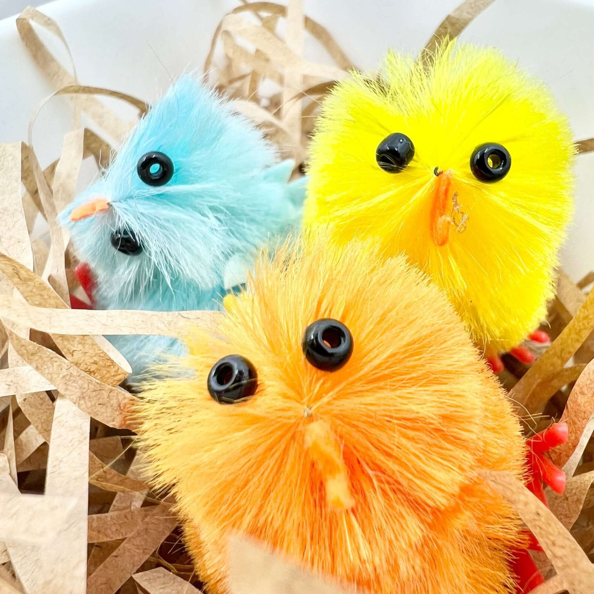 Close-up of blue, yellow and orange chick figures among shredded filler