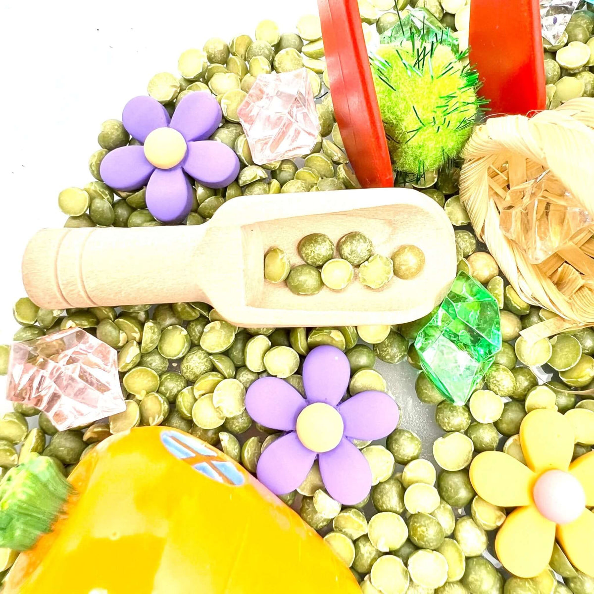 Scoop of green sensory filler among flowers and gems; the pictured carrot house is not included