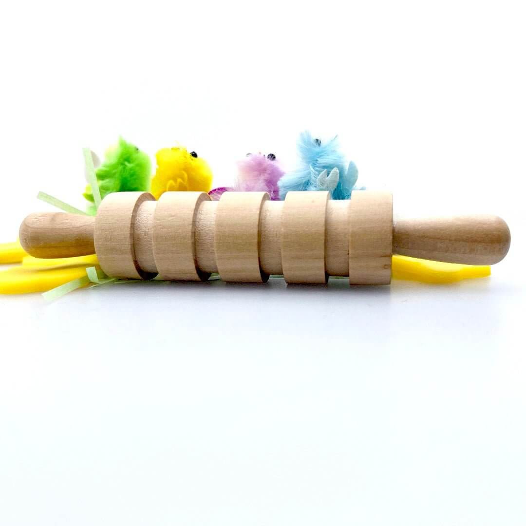 Grooved rolling pin in front of four colorful chick figures