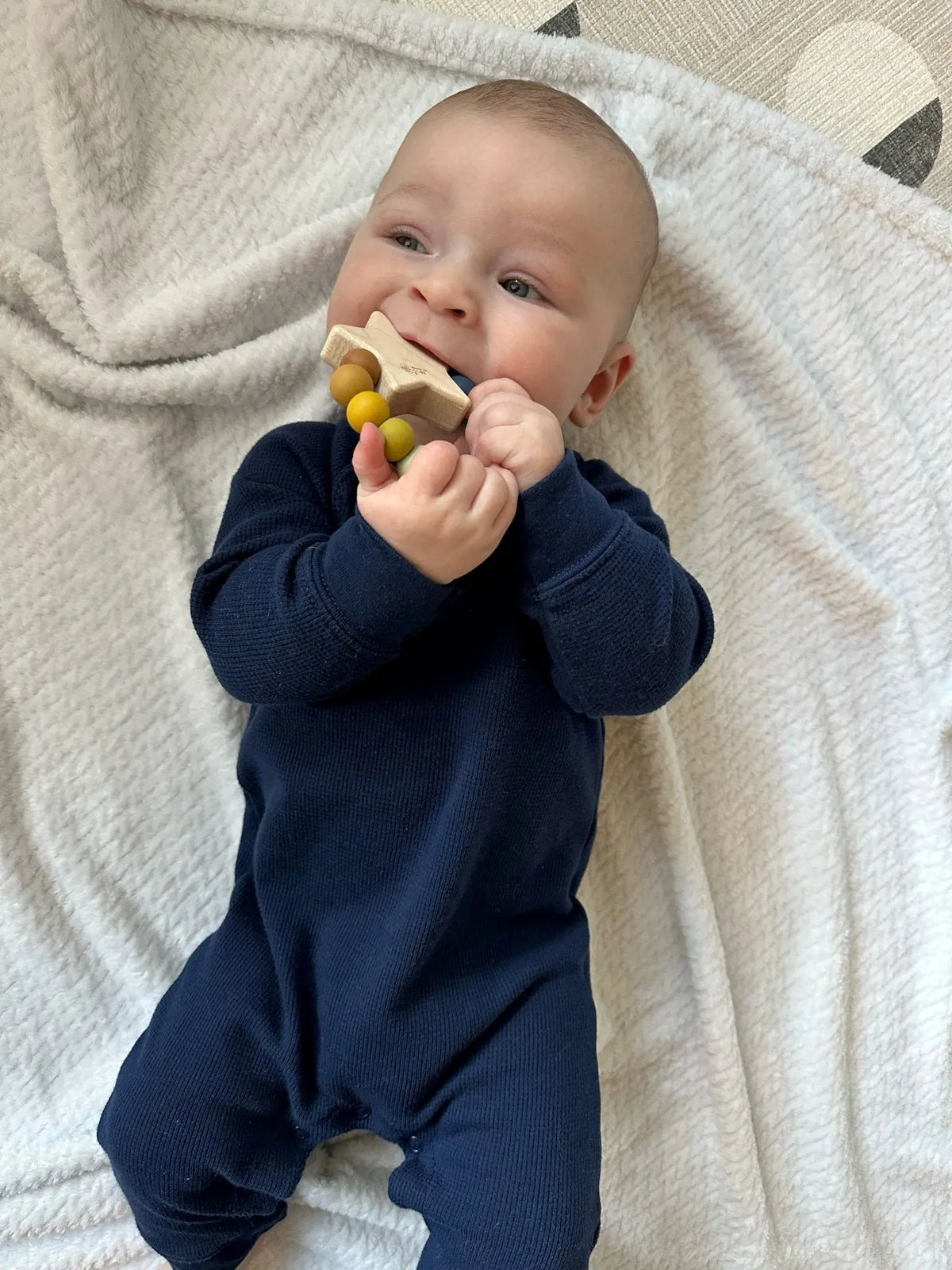 Lifestyle photo showing a wood and silicone teether with a child