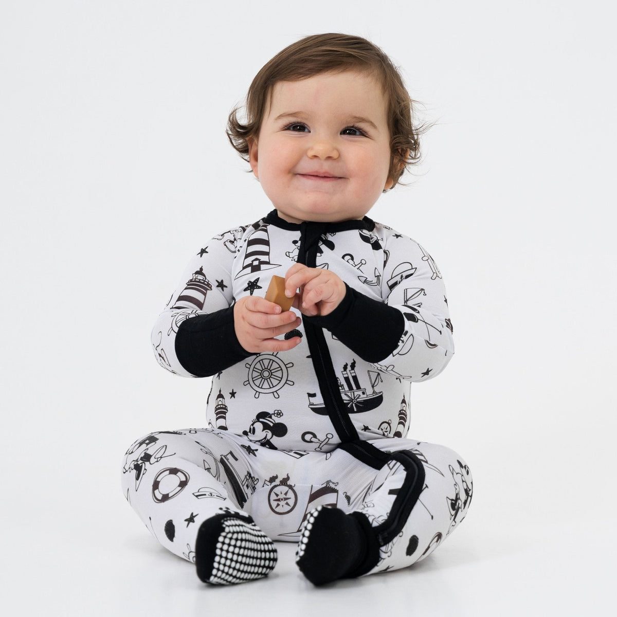Front view of a baby sitting in Bam & Stitch Steamboat Willie Convertible Romper.