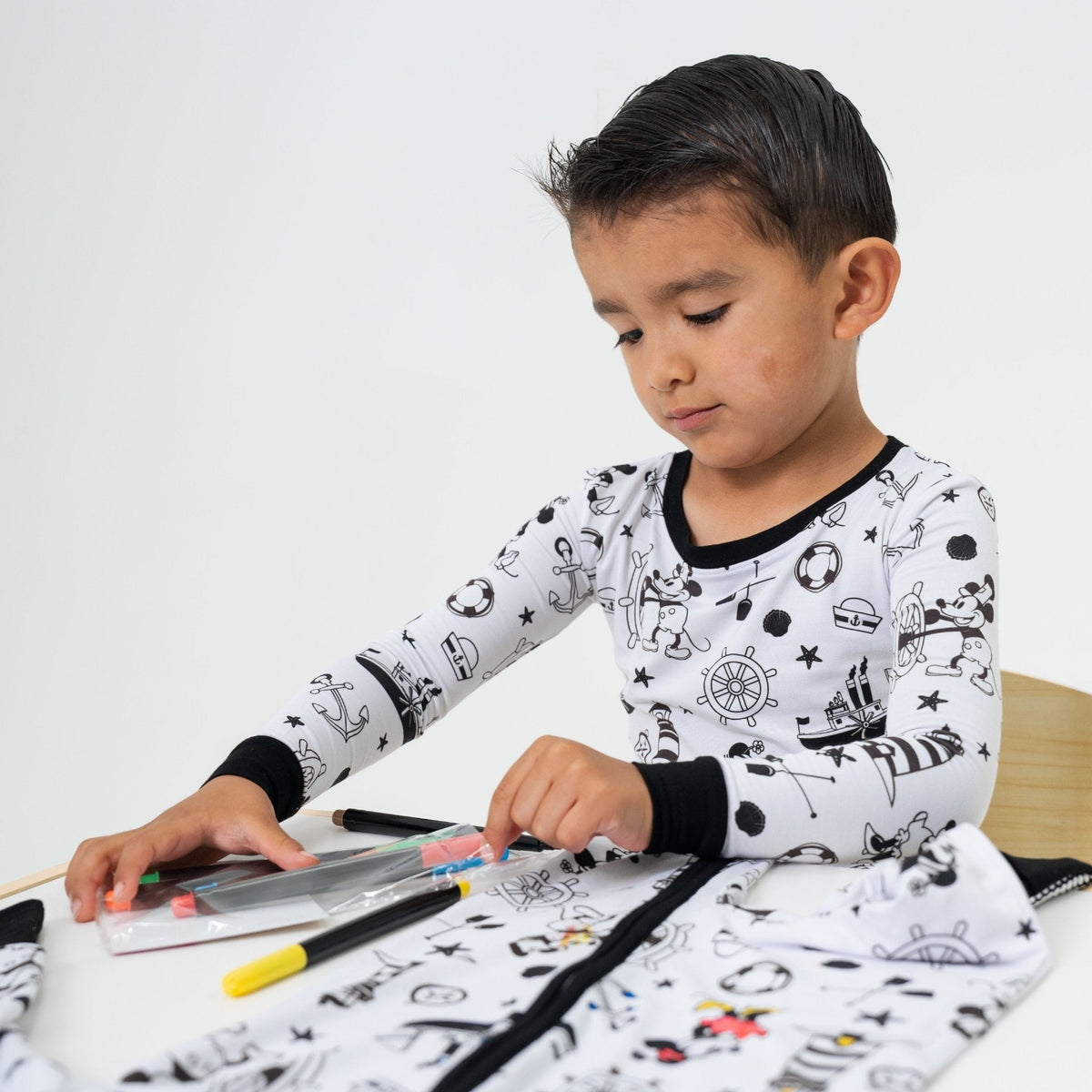 Child playing at a table while wearing Bam & Stitch Steamboat Willie Long Sleeve Pajamas.